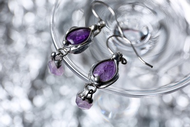 Closeup of beautiful pair of silver earrings with amethyst gemstones on blurred background