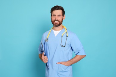 Photo of Happy doctor with stethoscope and clipboard on light blue background
