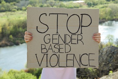 Photo of Woman holding sign with text Stop Gender Based Violence outdoors