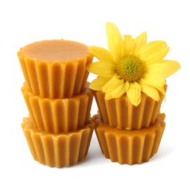 Photo of Stack of natural beeswax cake blocks and flower on white background