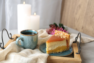 Cup of tea and delicious cheesecake on grey table