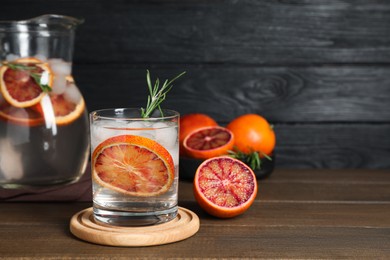 Delicious refreshing drink with sicilian orange and rosemary on wooden table. Space for text