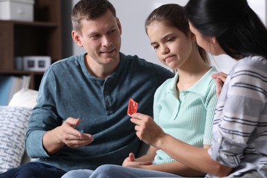 Parents talking with their teenage daughter about contraception at home. Sex education concept