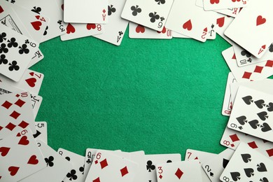 Photo of Frame made of playing cards on green table, top view. Space for text