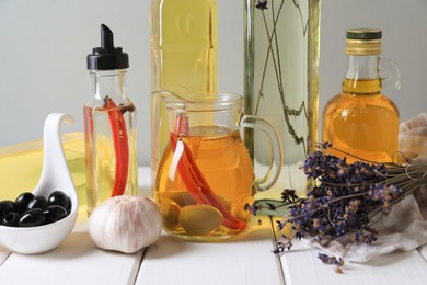 Photo of Different cooking oils and ingredients on white wooden table against grey background