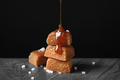 Pouring delicious salted caramel on candies against black background
