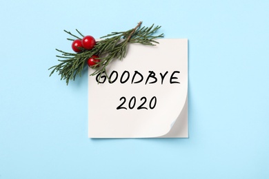 Photo of Memory sticker with text Goodbye 2020, thuja branch and red berries on light blue background, flat lay