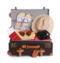 Open vintage suitcase with clothes packed for summer vacation isolated on white