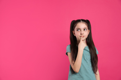 Pensive little girl on pink background, space for text. Thinking about answer to question