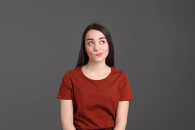 Portrait of emotional young woman on dark grey background. Personality concept