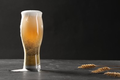 Photo of Glass of beer and spikes on black table. Space for text
