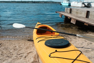 Yellow kayak with paddle on beach near river. Summer camp activity