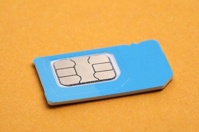 Mini SIM card on orange background, closeup