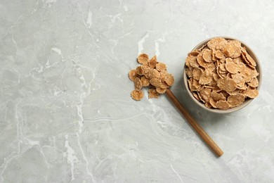 Ceramic bowl with wheat flakes on grey table, flat lay and space for text. Cooking utensil