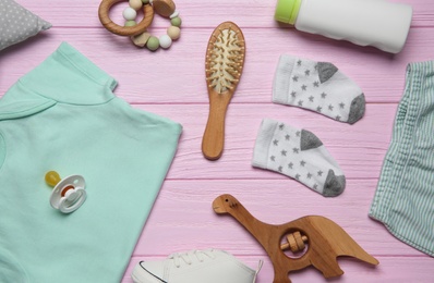 Baby clothes and accessories on pink wooden background, flat lay