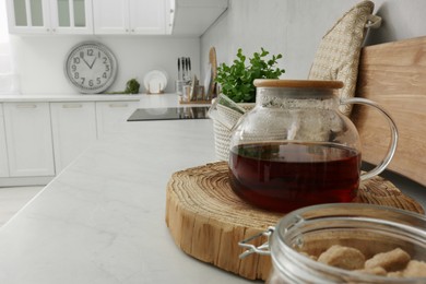 Photo of Stylish glass tea pot on white marble countertop in kitchen