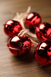 Shiny red sleigh bells on wooden table, closeup