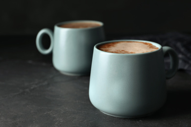 Cups of delicious hot cocoa on grey table. Space for text