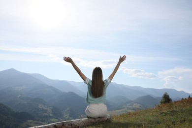 Photo of Young woman in peaceful mountains, back view. Feeling freedom