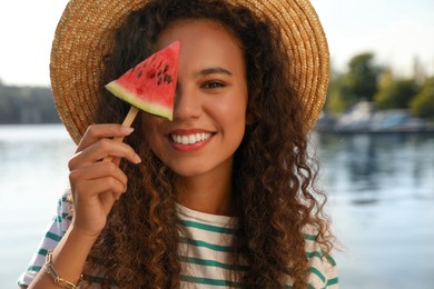 Photo of Beautiful young African American woman with piece of watermelon near river