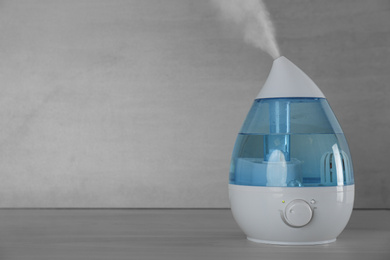 Modern air humidifier on table against grey background. Space for text