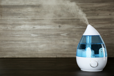 Modern air humidifier on wooden table. Space for text