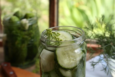 Photo of Glass jar with cucumber slices, dill and brine on table indoors, closeup. Pickling recipe