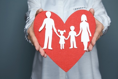 Woman holding red heart and paper family cutout, closeup