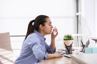 Sick young woman with napkin in office