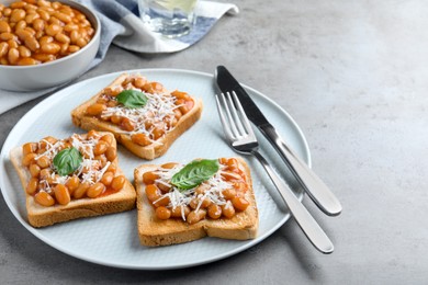 Toasts with delicious canned beans on light grey table