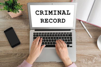 Image of Woman using laptop with words CRIMINAL RECORD at table, top view