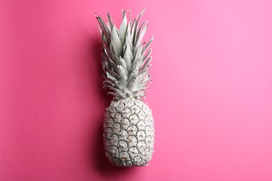 Photo of Painted white pineapple on pink background, top view. Creative concept