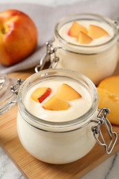 Delicious yogurt with fresh peach on white table, closeup