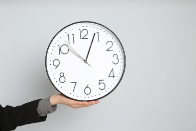 Businesswoman holding clock on light grey background, closeup with space for text. Time management