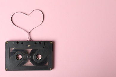 Top view of music cassette and heart made with tape on pink background, space for text. Listening love song