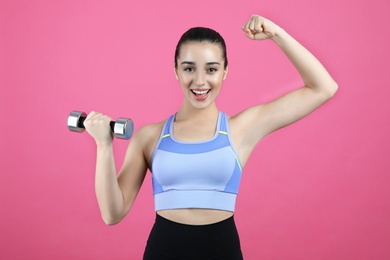 Woman with dumbbell as girl power symbol on pink background. 8 March concept