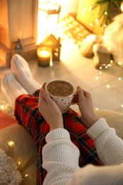 Woman with cup of hot drink at home, closeup. Christmas celebration