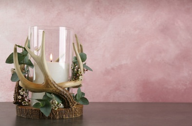 Burning candle in beautiful glass holder with eucalyptus on wooden table, space for text