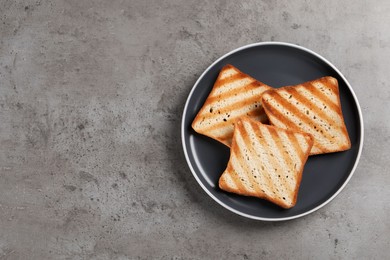 Photo of Plate with slices of delicious toasted bread on gray table, top view. Space for text