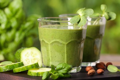 Glasses of fresh green smoothie and ingredients on wooden table, closeup
