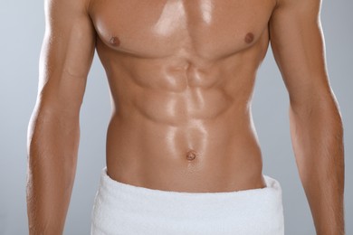 Shirtless man with slim body and towel wrapped around his hips on grey background, closeup