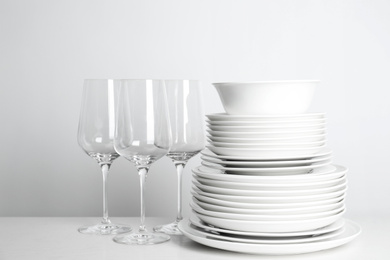 Stack of clean plates and glasses on white background