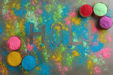Word Holi and colorful powder dyes on grey background, flat lay