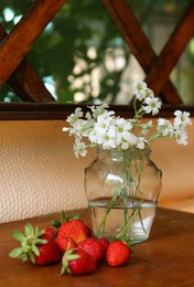 Photo of Fresh strawberries and bouquet of beautiful white flowers on wooden table