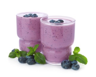 Photo of Glasses of blueberry smoothie with fresh berries and mint on white background