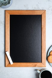 Clean small chalkboard, coffee and cookies on light grey table, flat lay