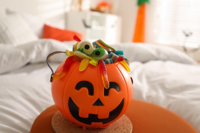Halloween trick or treat bucket with different sweets on bed indoors