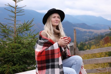 Young woman with mug of hot drink in mountains
