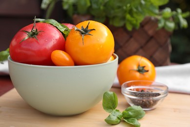 Different sorts of tomatoes, and basil on wooden table