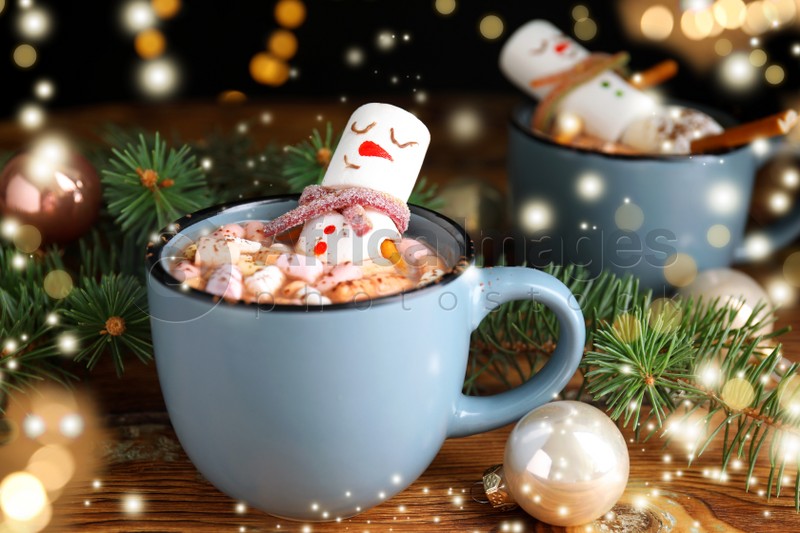 Marshmallow snowman in cup with hot drink on wooden table. Bokeh effect 